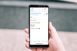 Hånd med mobil, hvor der vises en mail med emojies